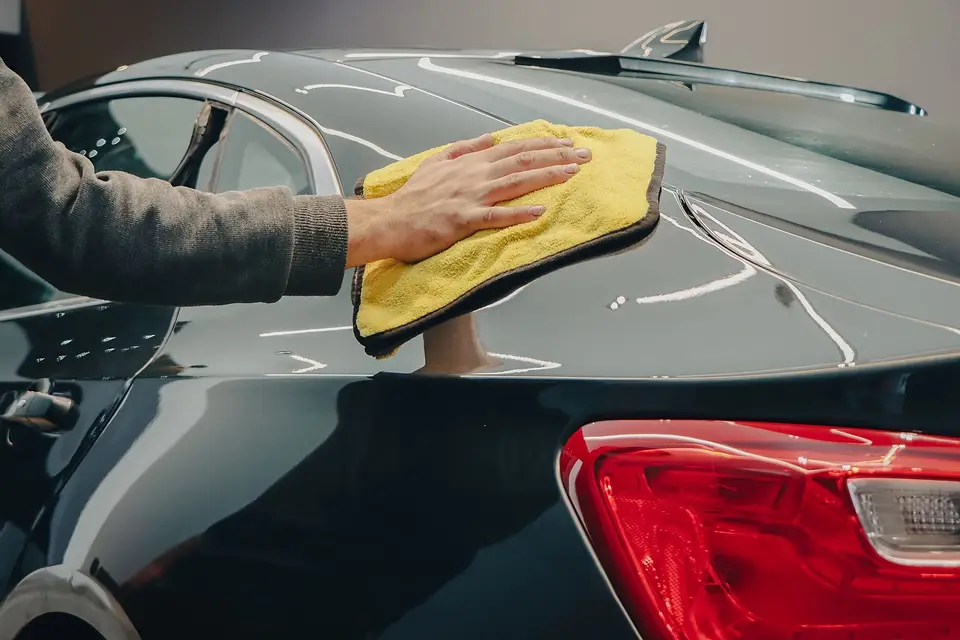 Hand drying a black car with a soft microfiber towel