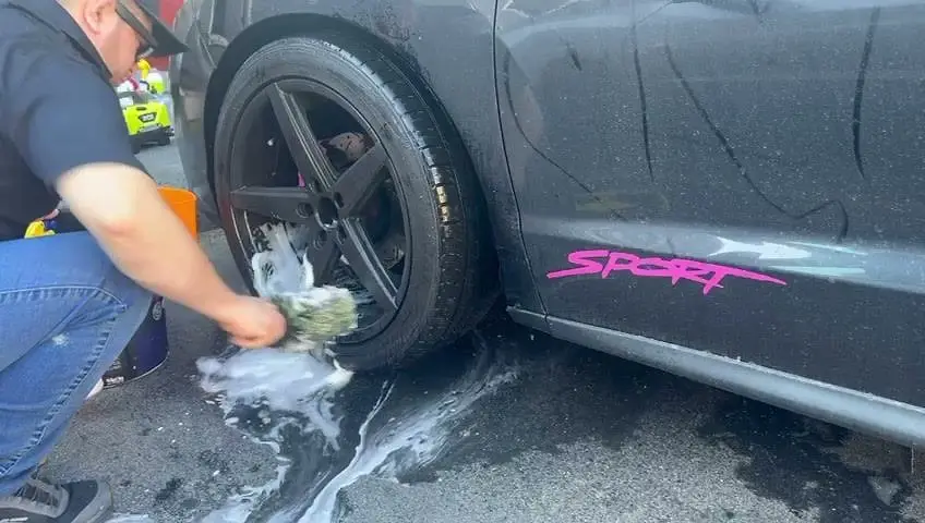 Josue brushing a wheel with soapy water, one spoke at a time
